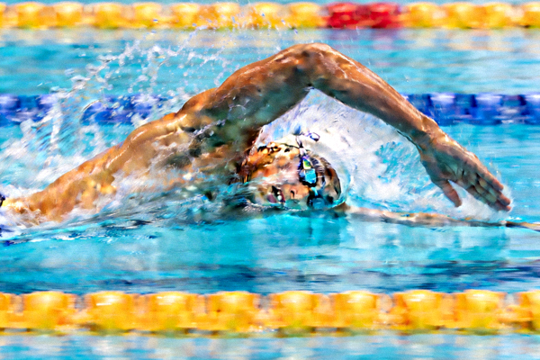 游泳运动员在蓝色泳池中破浪前进的侧面视角